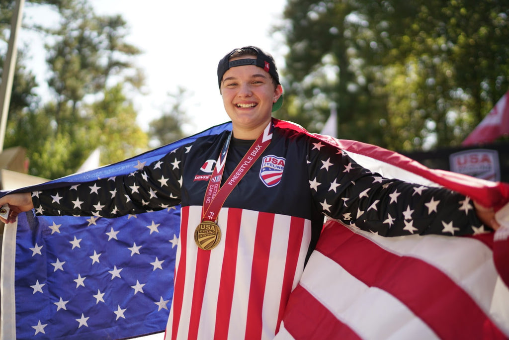 BMX Freestyle Cyclist Hannah Roberts draped in an American Flag with medals around her neck